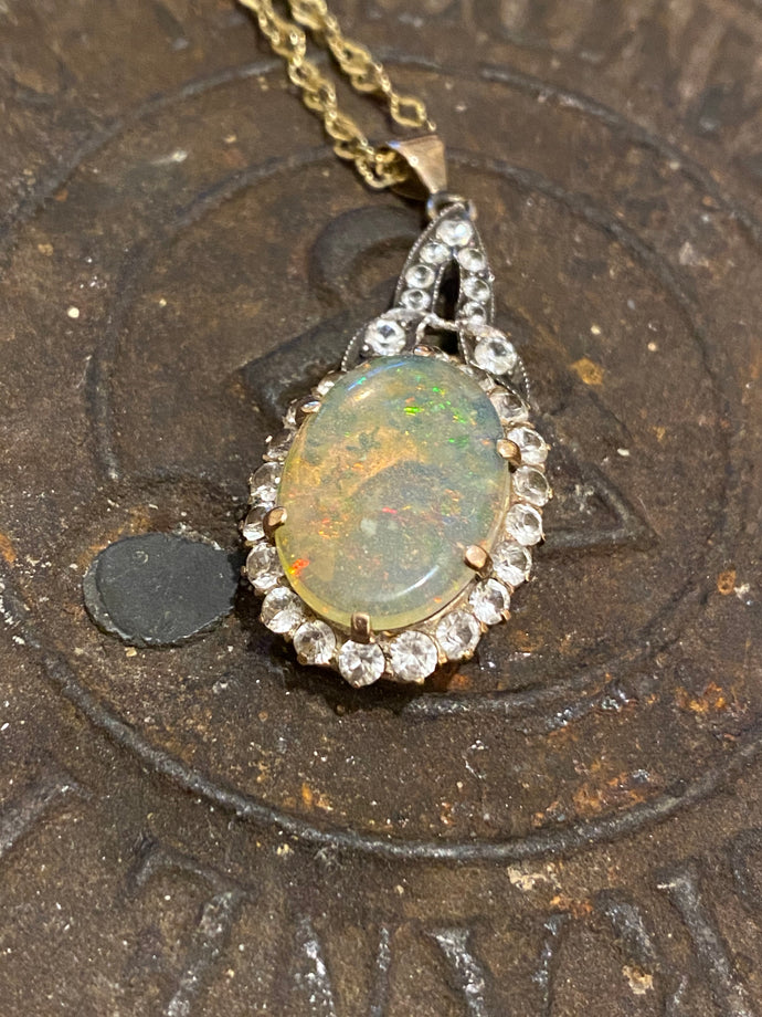 An early 20th century unmarked gold cabochon fire opal and white sapphire pendant